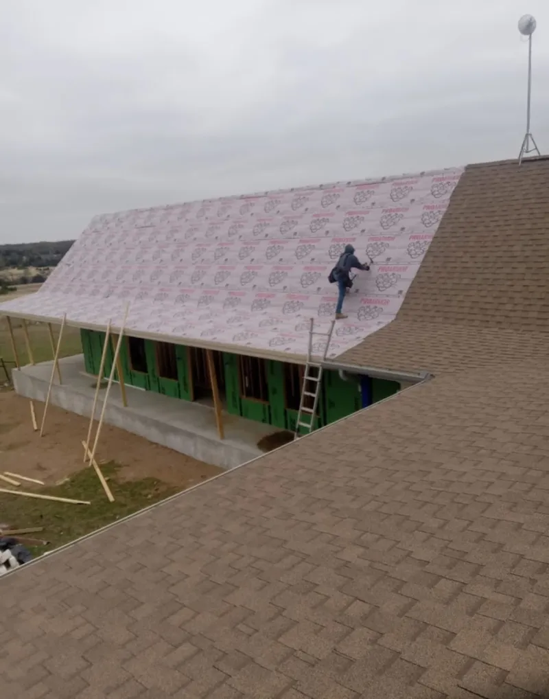 Worker preparing underlayment for a metal roof installation in Fort Meade